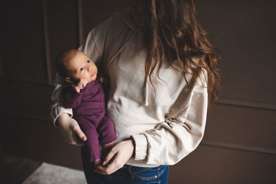 Midsection of woman carrying daughter at home