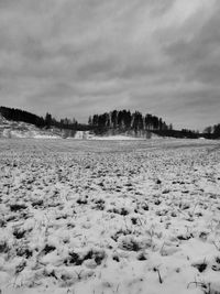 Snow covered landscape against cloudy sky