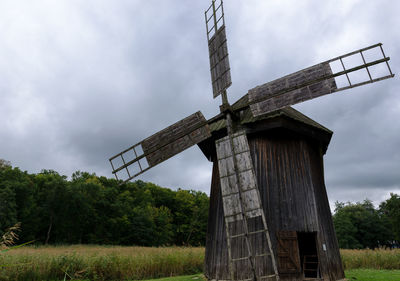 Scenic view of traditional windmill on field against storm cloud