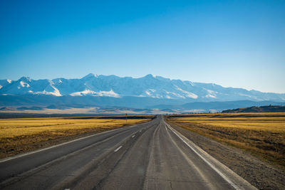 Empty road against clear blue sky