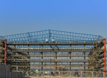 Low angle view of construction site against clear blue sky