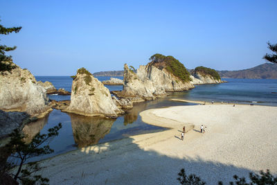 Rocks on beach against clear blue sky