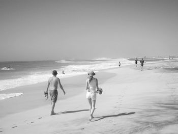 People walking on beach against clear sky