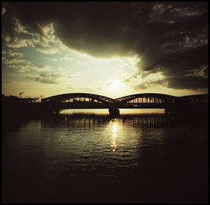 Bridge over river against sky at sunset