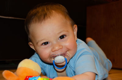 Portrait of cute boy with pacifier by toys