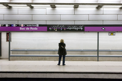 Rear view of woman standing at subway station