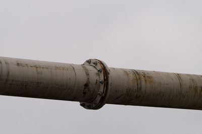 Low angle view of metallic pipeline against clear sky