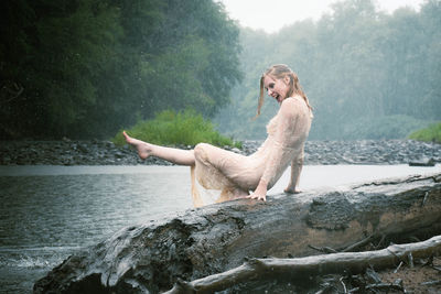 Woman sitting on rock against trees