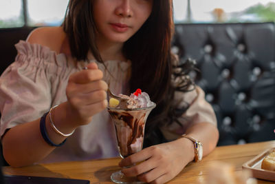 Midsection of woman holding ice cream in restaurant