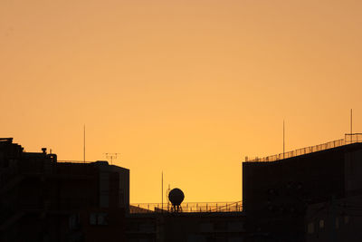 Silhouette of water tower against sky during sunset