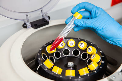 Scientist inserting a tube with a blood sample in a laboratory centrifuge. blood test