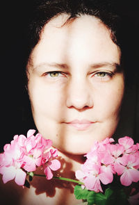 Close-up of woman with pink flowers against black background