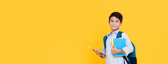 Portrait of smiling girl standing against yellow background