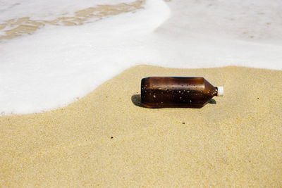 High angle view of bottle on sand at shore