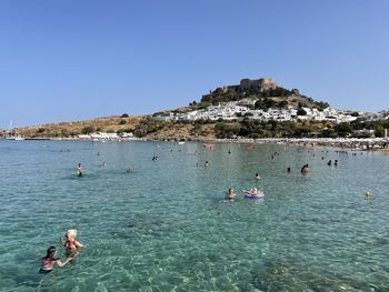 People swimming in sea against clear sky