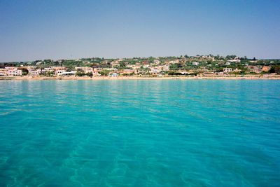 Scenic view of sea and buildings against clear sky
