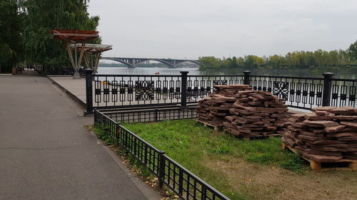 Stack of wooden railing by bridge against sky