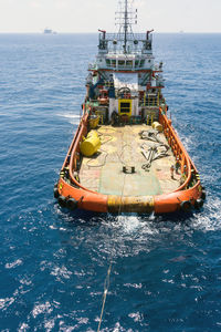 An anchor handling tug boat performing anchor deployment for a construction work barge at offshore