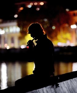 Silhouette man playing flute at night