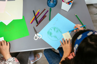 Female student drawing concepts about how to save the planet over cardboard in classroom