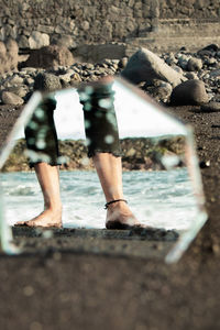 Low section of man standing on rock by sea