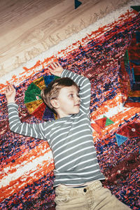 High angle view of boy lying down on rug at home