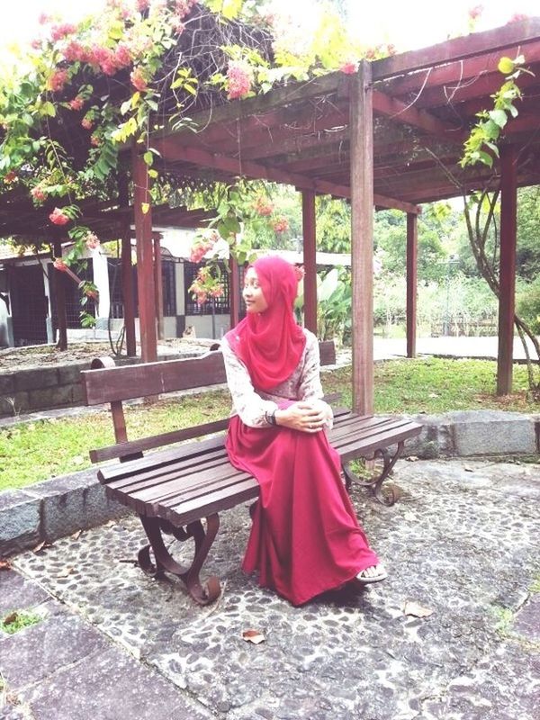 red, built structure, tree, architecture, park - man made space, religion, day, sculpture, sunlight, sitting, pink color, cultures, tradition, traditional clothing, full length, outdoors, art, flower