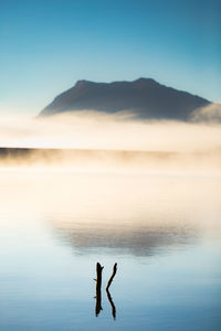 Scenic view of lake against clear sky in foggy weather