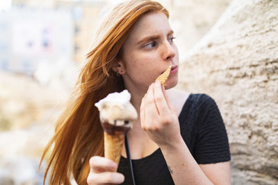 Young woman eating ice cream waffle cone