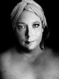 Close-up portrait of shirtless man with make-up against black background