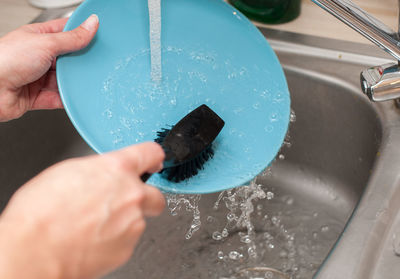 Cropped hands cleaning dish