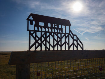 Low angle view of metal structure on field against sky