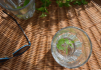 High angle view of drinking glass and sunglass on wicker seat