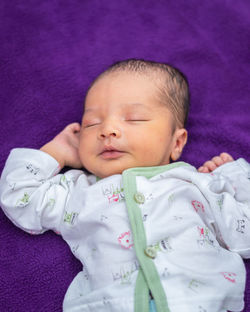 Newborn baby isolated sleeping in white cloth with purple background from different angle