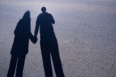 Shadow of couple holding hands on road