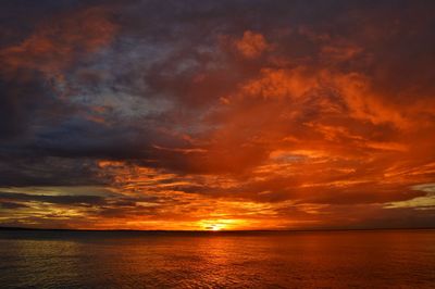 Scenic view of sea against dramatic sky during sunset