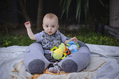 Portrait of cute baby boy sitting on bed