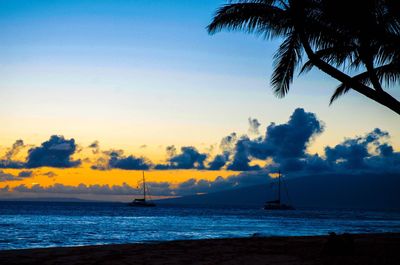 Boats in calm sea at sunset