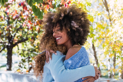 Two female afro american happy best friends hugging each other and laughing in the park 