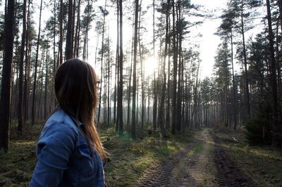 Woman standing against trees at forest