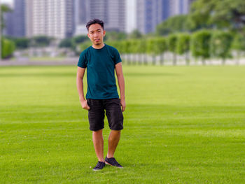 Portrait of young man standing on grassy field