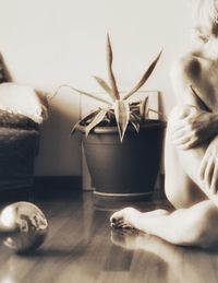 Woman sitting by potted plant on table at home