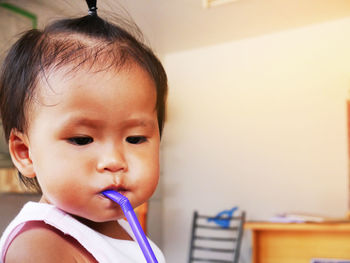 Close-up of cute baby with drinking straw at home