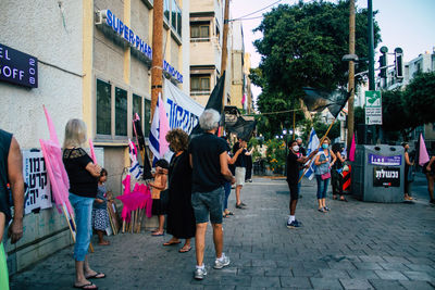 People walking on street amidst buildings in city