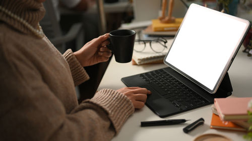 Midsection of woman using laptop on table