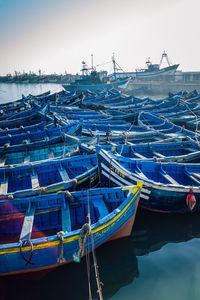 Fishing boats moored at harbor against clear blue sky