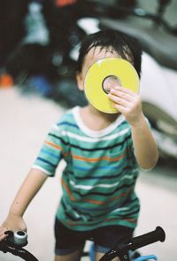 Boy holding compact disc while riding bicycle on floor