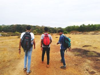 Rear view of people walking on road against sky