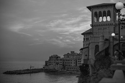 Building by sea against cloudy sky