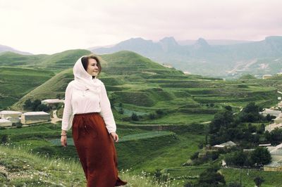Young woman standing on caucasus mountains against sky